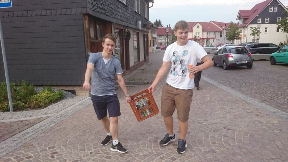Marius und Kevin tragen einen Wasserkasten